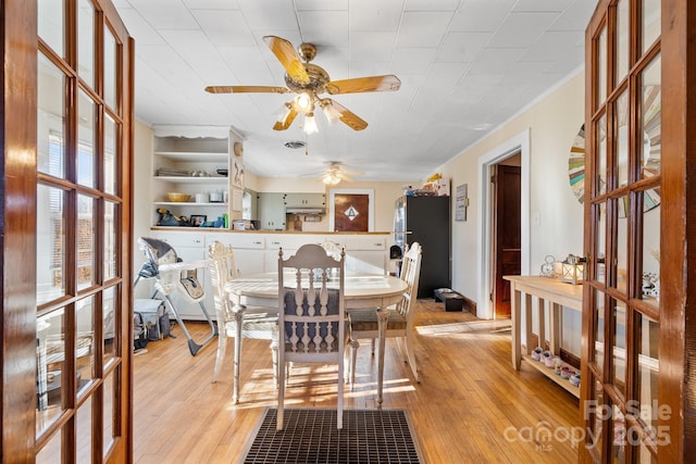 dining space with ceiling fan, built in features, ornamental molding, and light hardwood / wood-style flooring