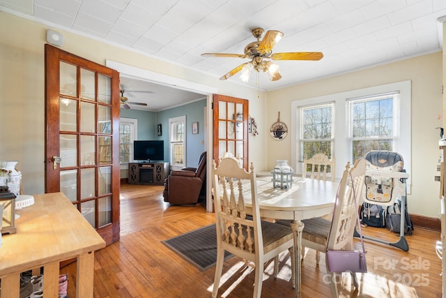 dining area with light wood-type flooring, ceiling fan, french doors, and ornamental molding