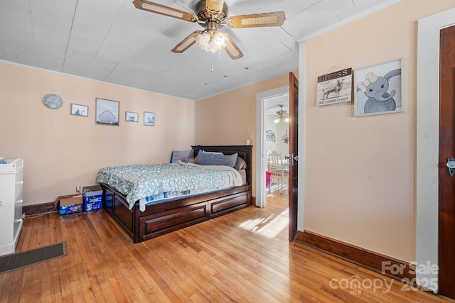 bedroom with light hardwood / wood-style floors, ceiling fan, and ornamental molding