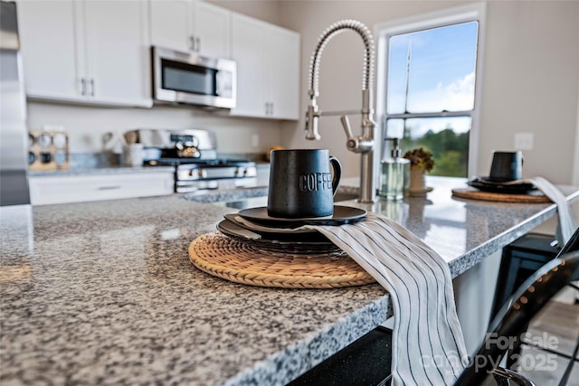 25 Amys Way, Black Mountain, NC 28711 - kitchen view of stainless steel microwave, range with gas stovetop, white cabinets, light stone countertops, and a kitchen breakfast bar