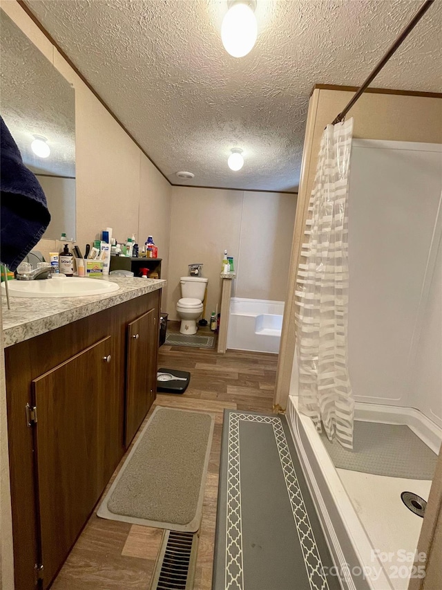 full bathroom featuring vanity, plus walk in shower, toilet, and a textured ceiling