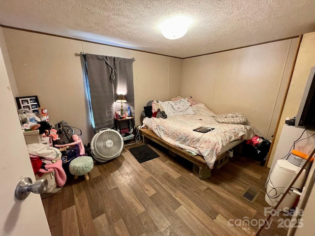 bedroom featuring ornamental molding, hardwood / wood-style floors, and a textured ceiling