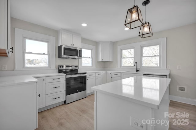 kitchen featuring decorative light fixtures, white cabinetry, and appliances with stainless steel finishes