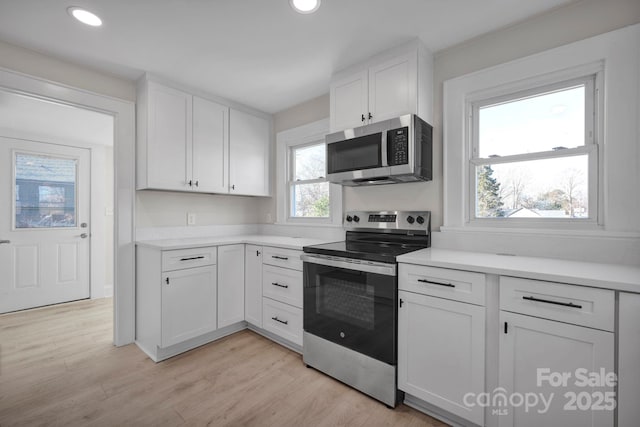 kitchen with white cabinets, light hardwood / wood-style floors, and stainless steel appliances