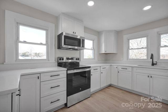 kitchen with sink, white cabinets, plenty of natural light, and appliances with stainless steel finishes