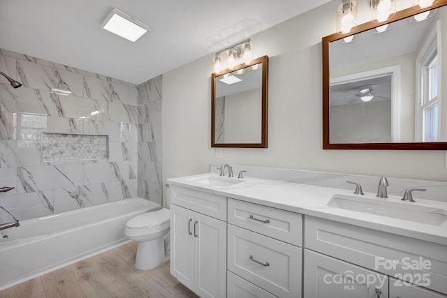 full bathroom featuring vanity, toilet, hardwood / wood-style flooring, and tiled shower / bath combo