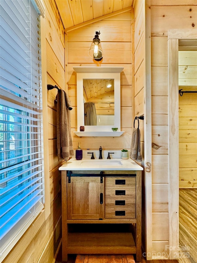 bathroom featuring vanity, wood ceiling, wooden walls, and vaulted ceiling