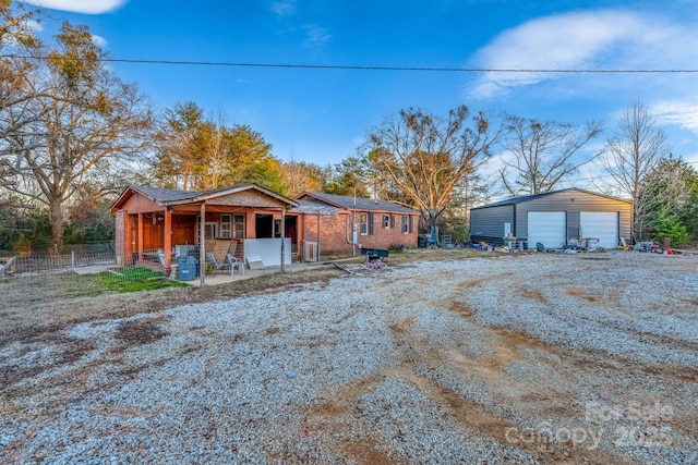 ranch-style house with a porch, a garage, and an outbuilding