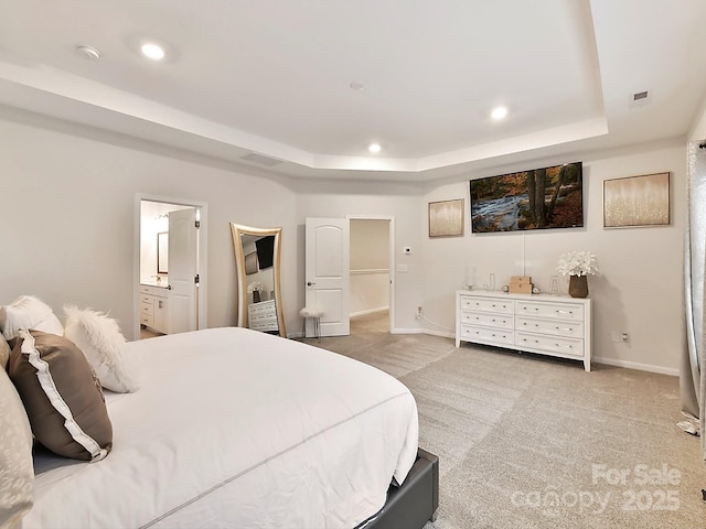 carpeted bedroom featuring a raised ceiling and ensuite bathroom