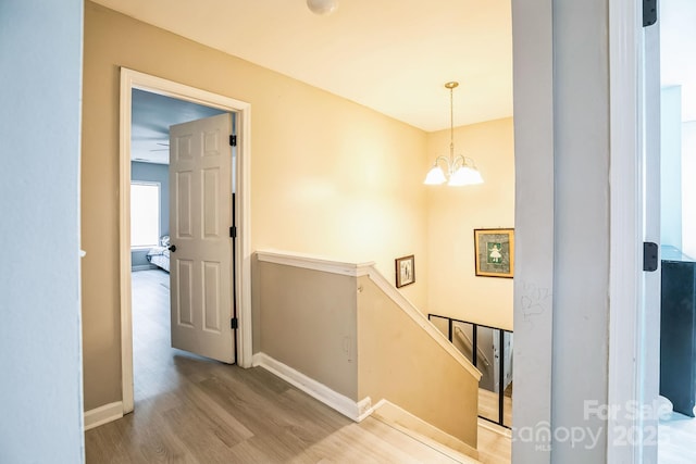 hallway with a notable chandelier and hardwood / wood-style flooring