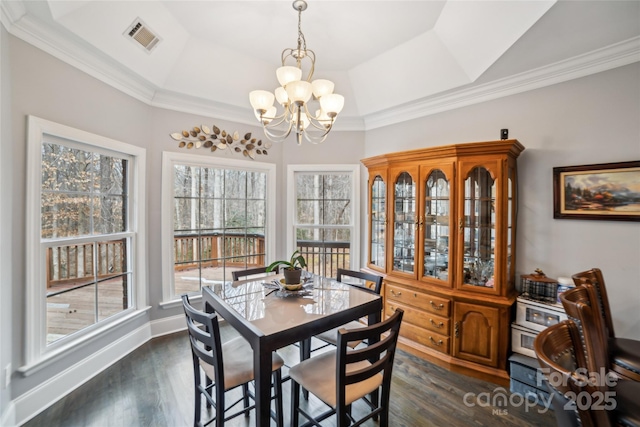 dining room with dark wood-type flooring, an inviting chandelier, vaulted ceiling, ornamental molding, and a tray ceiling