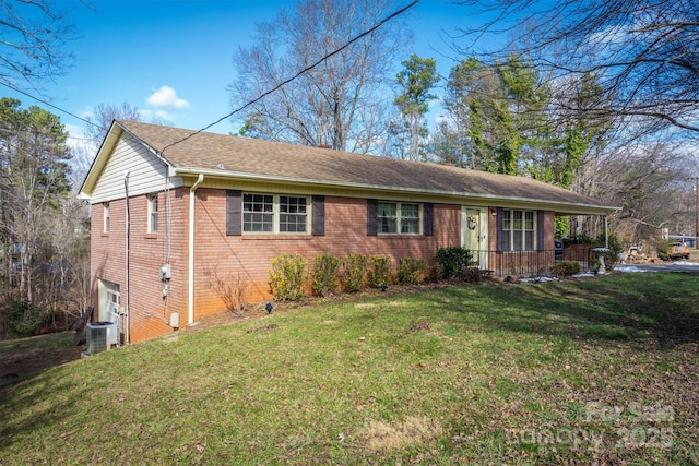 ranch-style house with covered porch, cooling unit, and a front yard