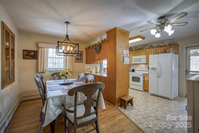 dining room with ceiling fan with notable chandelier, baseboard heating, and light wood-type flooring