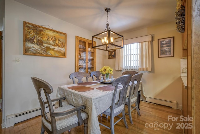 dining room featuring light hardwood / wood-style floors, baseboard heating, and a notable chandelier