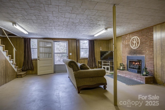 living room with a fireplace, concrete floors, and wooden walls