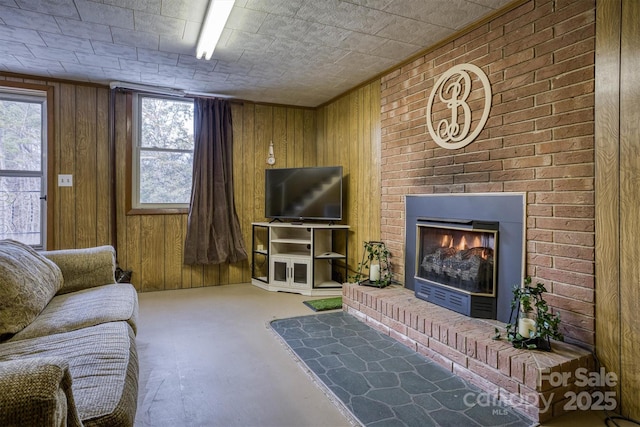 living room with a wealth of natural light, a large fireplace, concrete flooring, and wooden walls