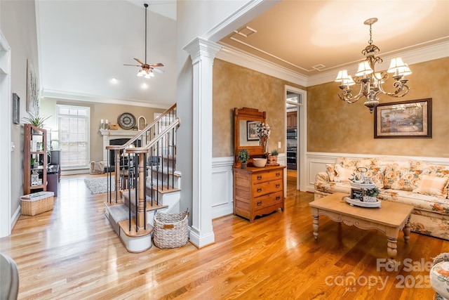 living room with ceiling fan with notable chandelier, ornamental molding, light wood-type flooring, and ornate columns