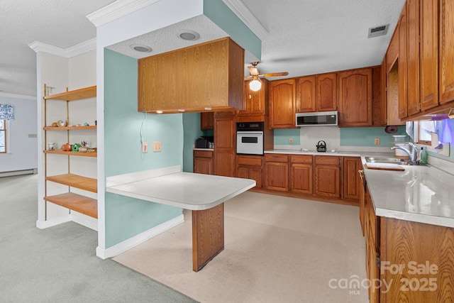 kitchen with crown molding, oven, sink, and a textured ceiling