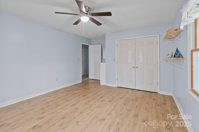 unfurnished bedroom with a textured ceiling, a closet, ceiling fan, and light hardwood / wood-style floors