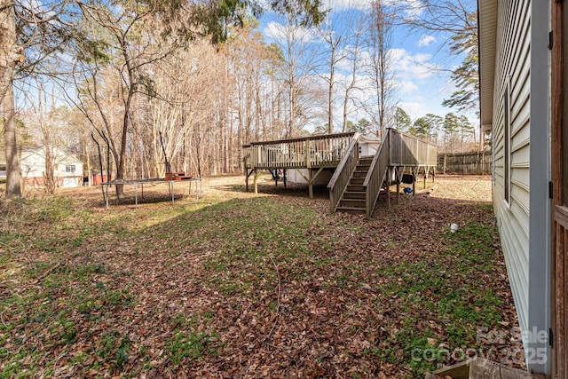 view of yard featuring a trampoline and a deck