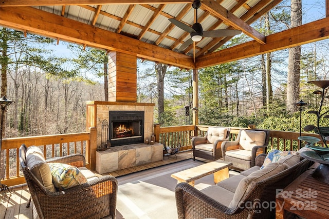 sunroom / solarium with ceiling fan, vaulted ceiling, and a tiled fireplace