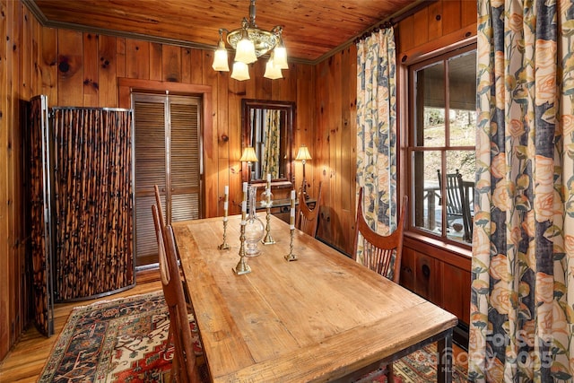 dining area featuring wood walls, wooden ceiling, and a chandelier