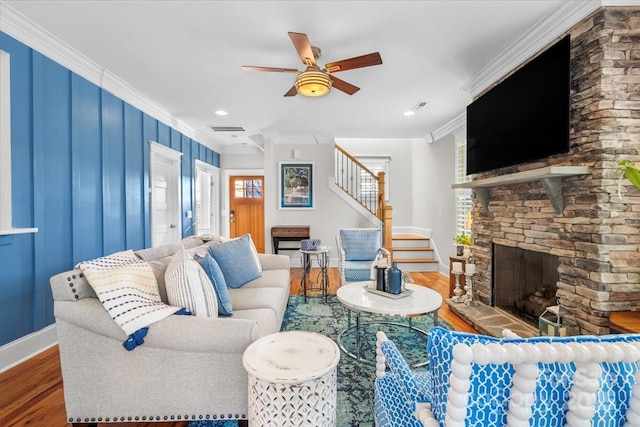 living room featuring crown molding, a fireplace, ceiling fan, and hardwood / wood-style flooring