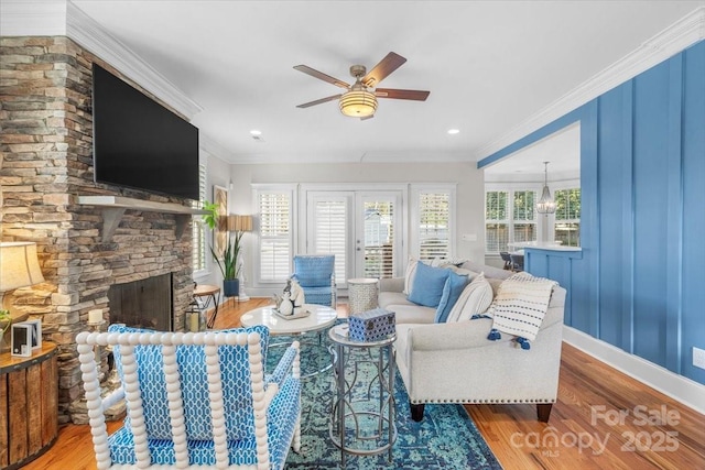 living room with hardwood / wood-style flooring, crown molding, a stone fireplace, and french doors