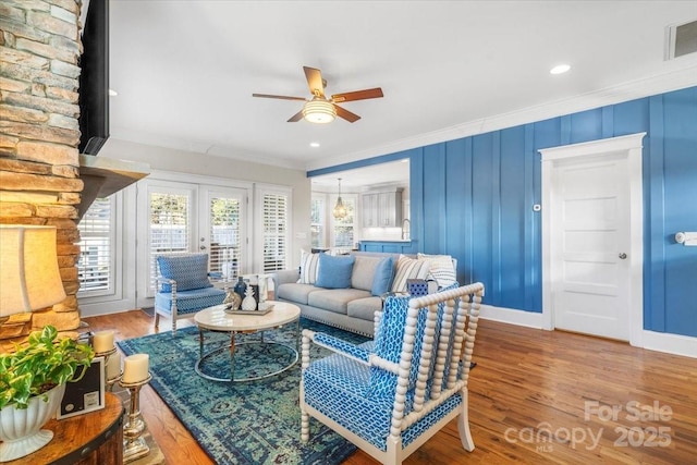 living room with crown molding, wood-type flooring, ceiling fan, and french doors