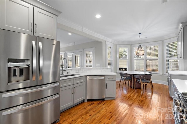 kitchen featuring sink, light hardwood / wood-style flooring, gray cabinets, appliances with stainless steel finishes, and ornamental molding