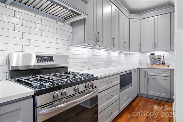 kitchen featuring gray cabinets, stainless steel appliances, dark hardwood / wood-style floors, tasteful backsplash, and custom range hood