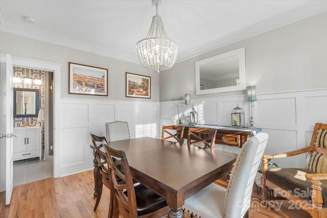 dining space featuring crown molding, a chandelier, and light hardwood / wood-style floors