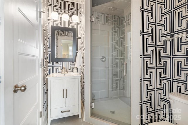 bathroom with tile patterned floors, vanity, toilet, and a shower with door