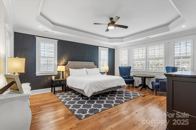 bedroom with crown molding, ceiling fan, a tray ceiling, and light hardwood / wood-style floors