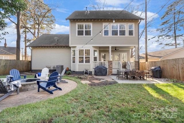 back of property with a yard, a patio area, and a fire pit