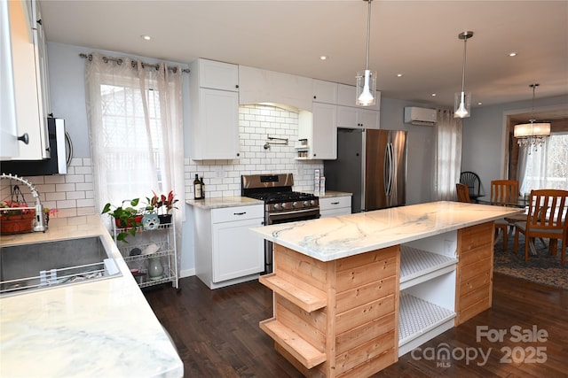 kitchen with appliances with stainless steel finishes, decorative light fixtures, white cabinets, a center island, and light stone counters