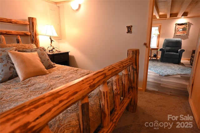 carpeted bedroom featuring beamed ceiling