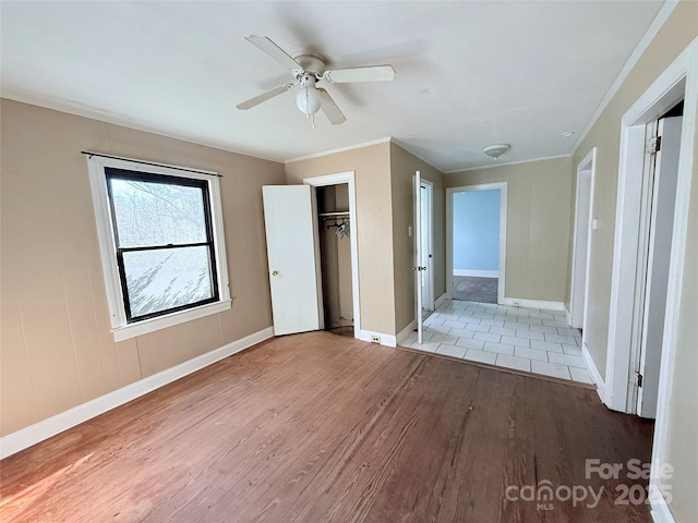 unfurnished bedroom featuring crown molding, ceiling fan, a closet, and light wood-type flooring