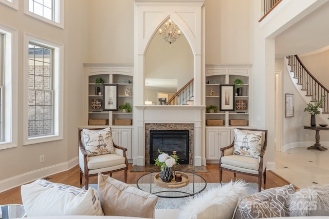 living room featuring built in shelves, a towering ceiling, a fireplace, and hardwood / wood-style flooring