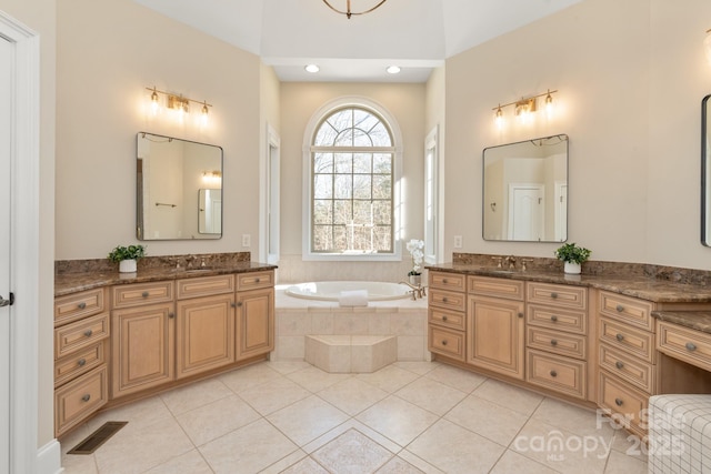 bathroom with vanity, a relaxing tiled tub, and tile patterned floors