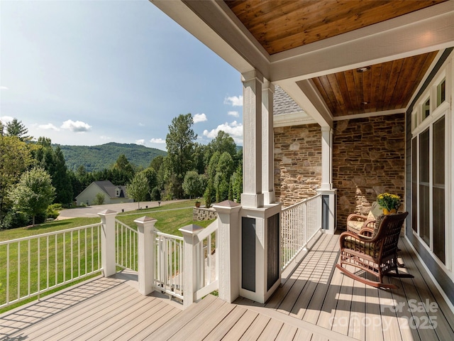 wooden terrace featuring a yard and a mountain view