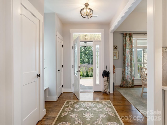 doorway to outside featuring a notable chandelier and dark wood-type flooring