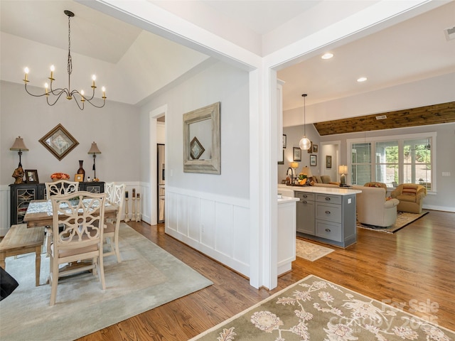 dining area with lofted ceiling, light hardwood / wood-style floors, and a notable chandelier