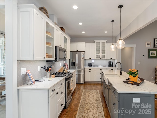 kitchen featuring sink, white cabinetry, decorative light fixtures, stainless steel appliances, and a kitchen island with sink