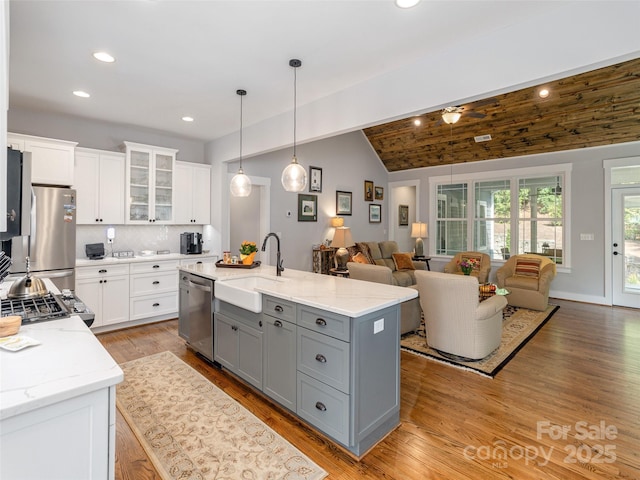 kitchen with white cabinetry, sink, stainless steel appliances, and an island with sink