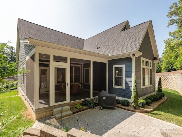 rear view of property featuring a sunroom and a patio area