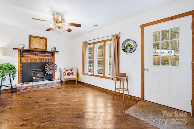 interior space with hardwood / wood-style flooring, a wood stove, a wealth of natural light, and ceiling fan