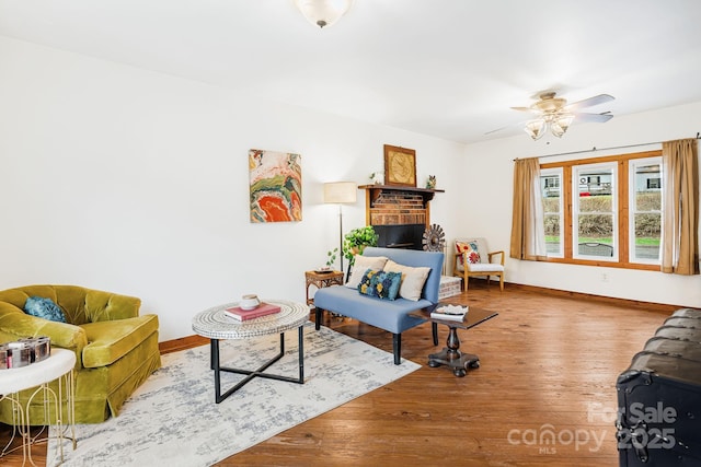 living room with a brick fireplace, hardwood / wood-style flooring, and ceiling fan