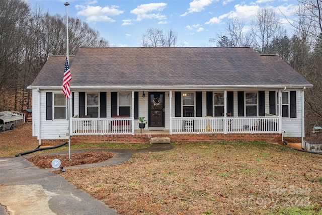 ranch-style home featuring covered porch and a front lawn