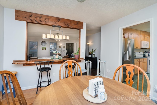 dining space with a textured ceiling and light wood-type flooring